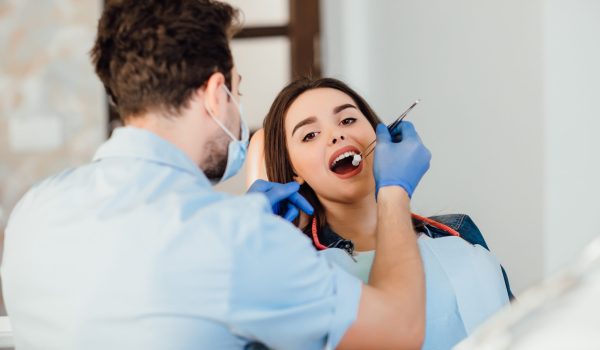 a dentist is checking a woman's teeth