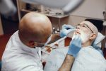 an old man is getting dental implant treatment from a dentist